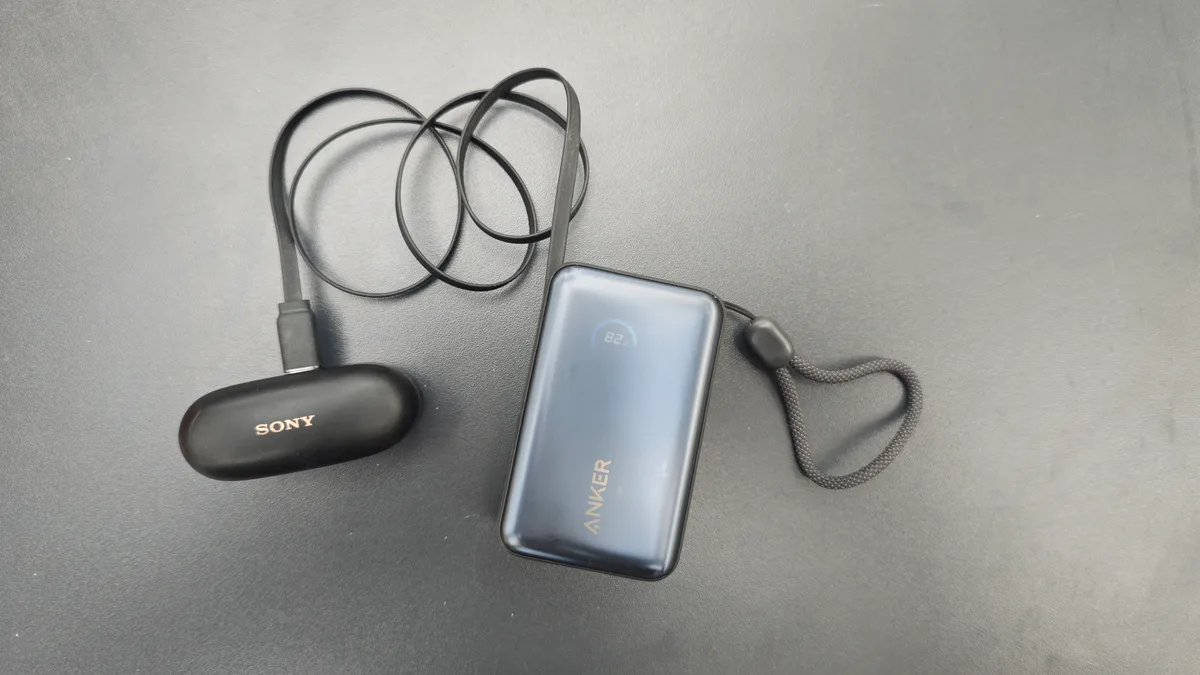 Anker Nano Powerbank mit weit ausgezogenem, integriertem Kabel beim Laden einer Sony-Kopfhörer-Ladehülle
