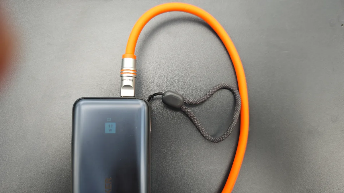 Anker Nano Powerbank mit orangefarbenem Ladekabel neben einer Sony-Kopfhörer-Ladehülle