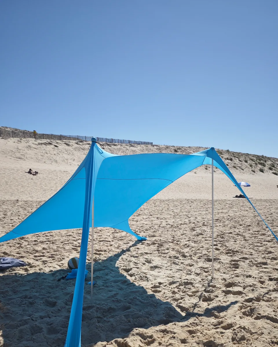 CUUPO Sonnensegel aufgebaut am Strand vor einer Düne, im Schatten liegen Ball und Tasche