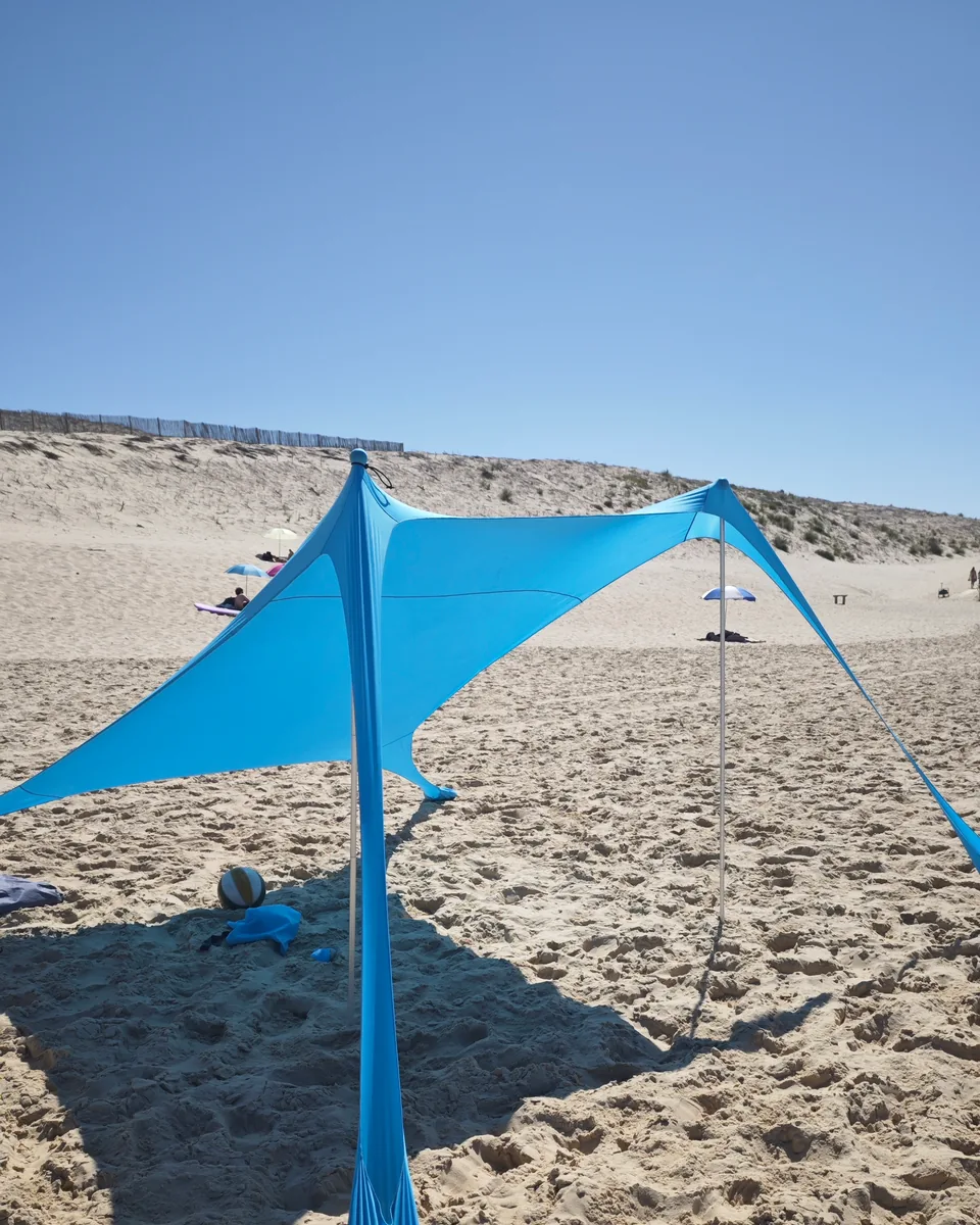 CUUPO Sonnensegel aufgebaut am Strand, Rückansicht mit Düne und Strandmuschel im Hintergrund