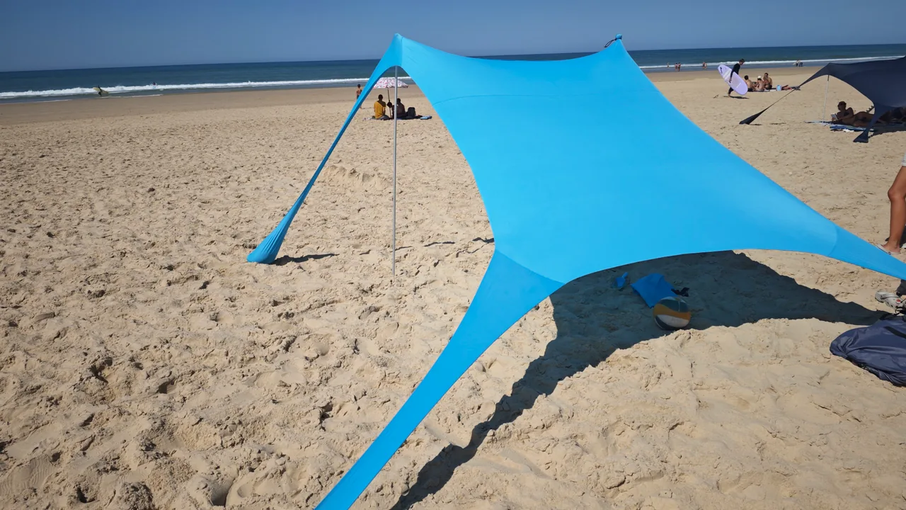 CUUPO Sonnensegel am belebten Strandabschnitt mit weiteren Sonnenschutzlösungen im Hintergrund